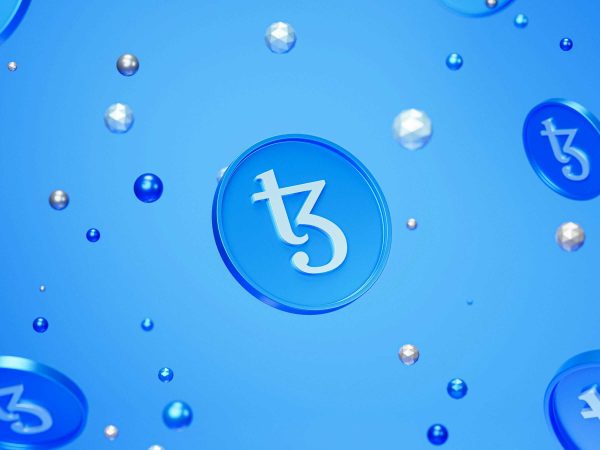 Blue coins with the Tezos cryptocurrency logo and various floating spheres are set against a light blue background.